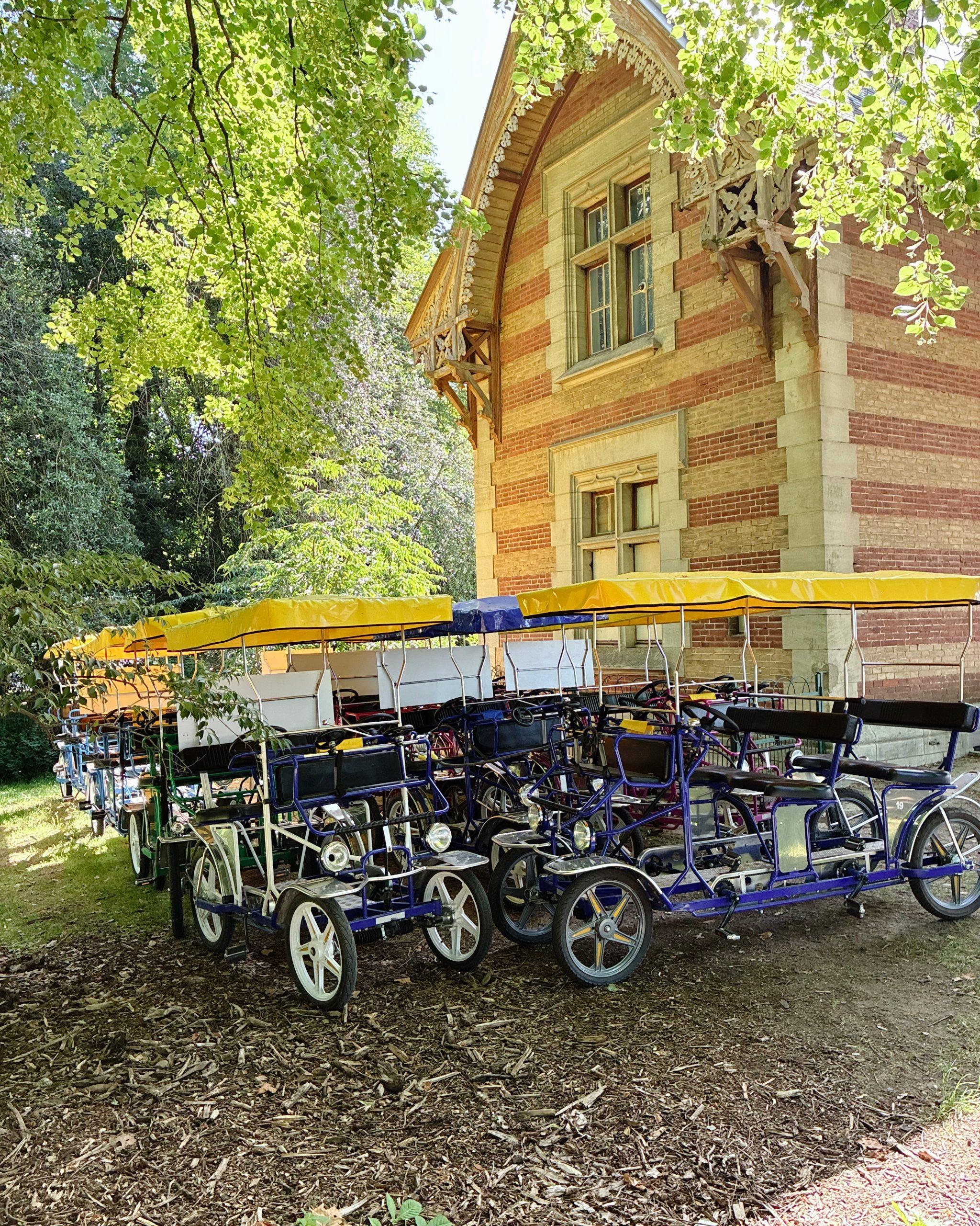 Vélos surrey à toit jaune garés devant un bâtiment en briques rouges entouré d'arbres
